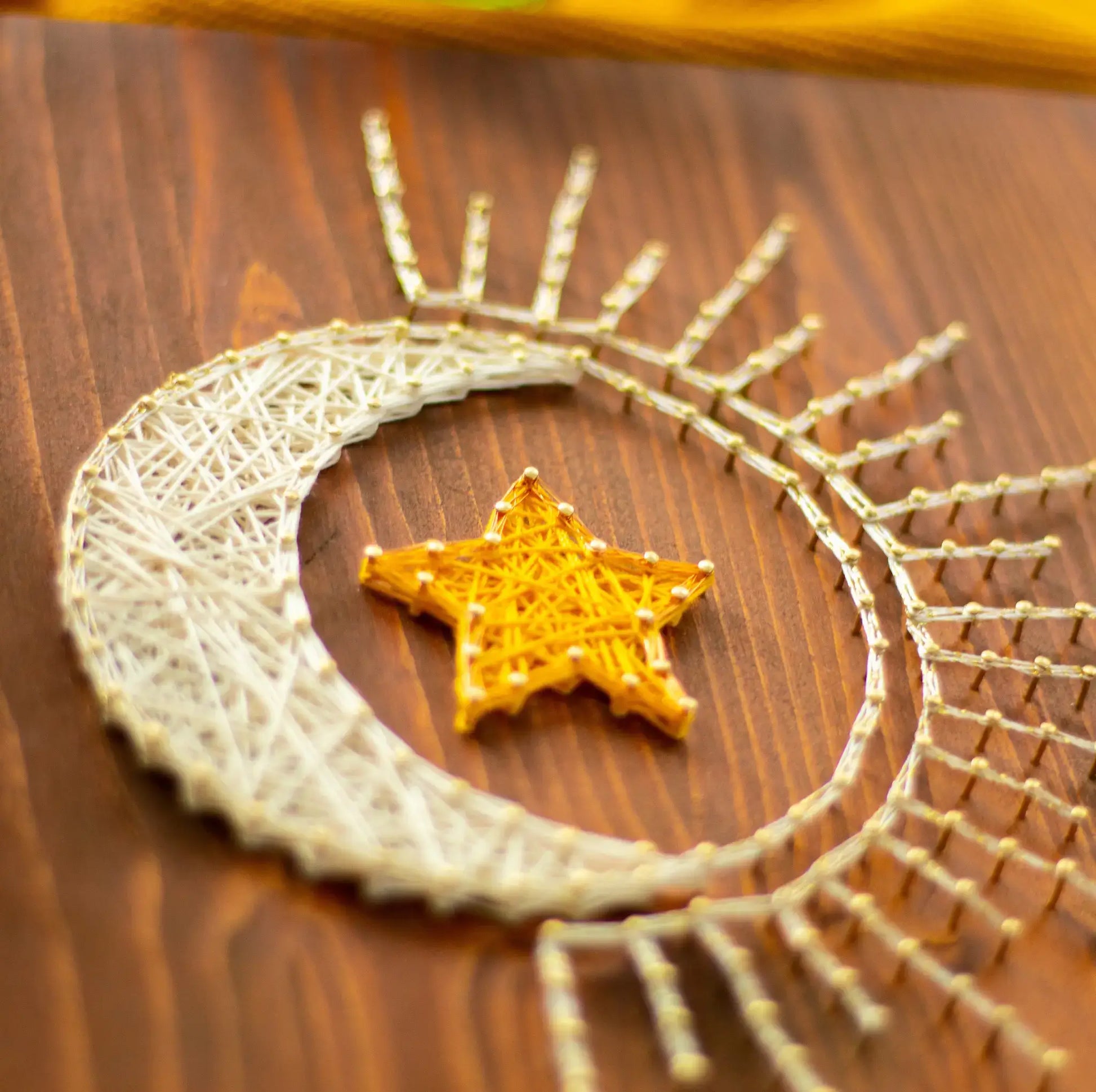 DIY string art kit featuring a crescent moon with a golden star created with threads on a wooden board by GoodStrings