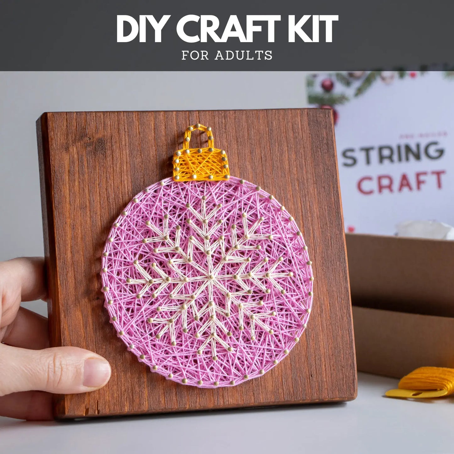DIY craft kit for adults with a string art ornament on a wooden board.