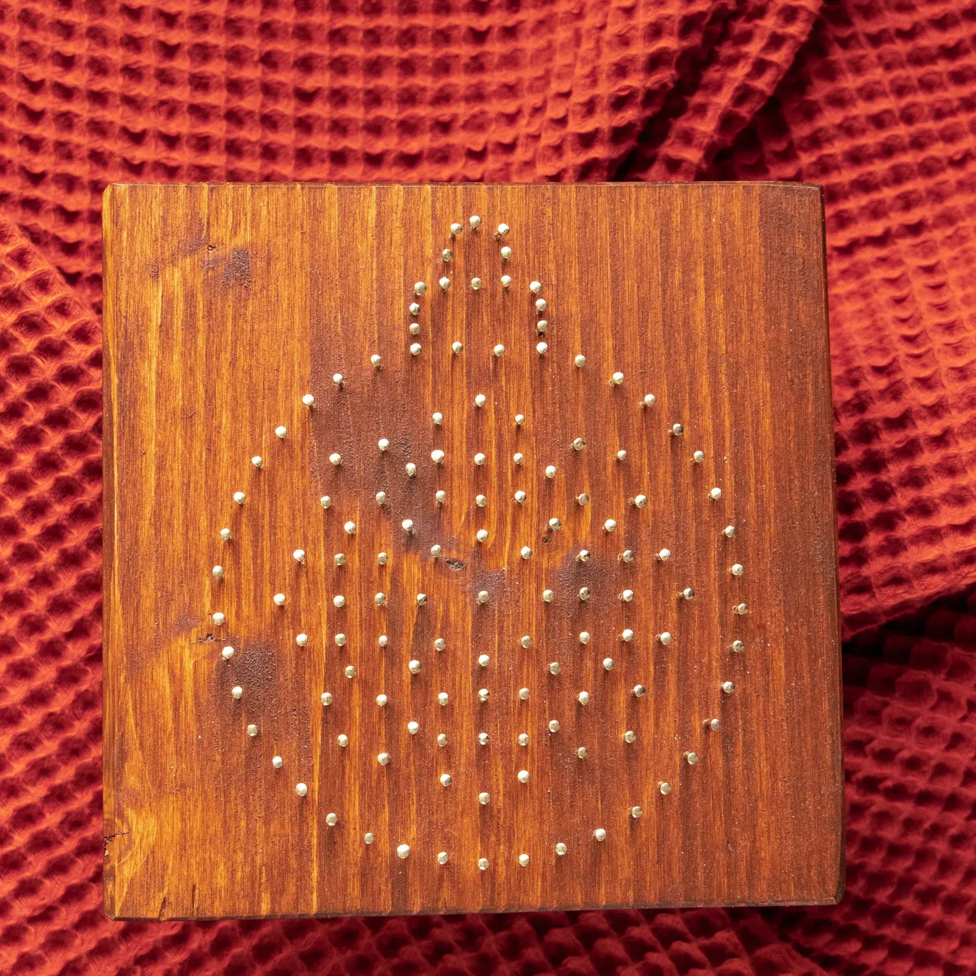 Wood board with pre-nailed outline for ornament string art pattern, nail placement preview.