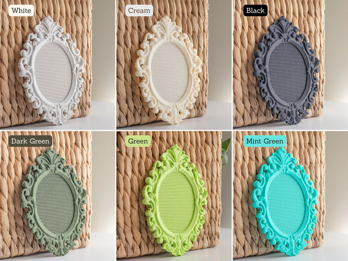 Ornate oval cross stitch frames in white, cream, black, dark green, green, and mint green, each shown against a woven background with the stitchable grid visible in the center.
