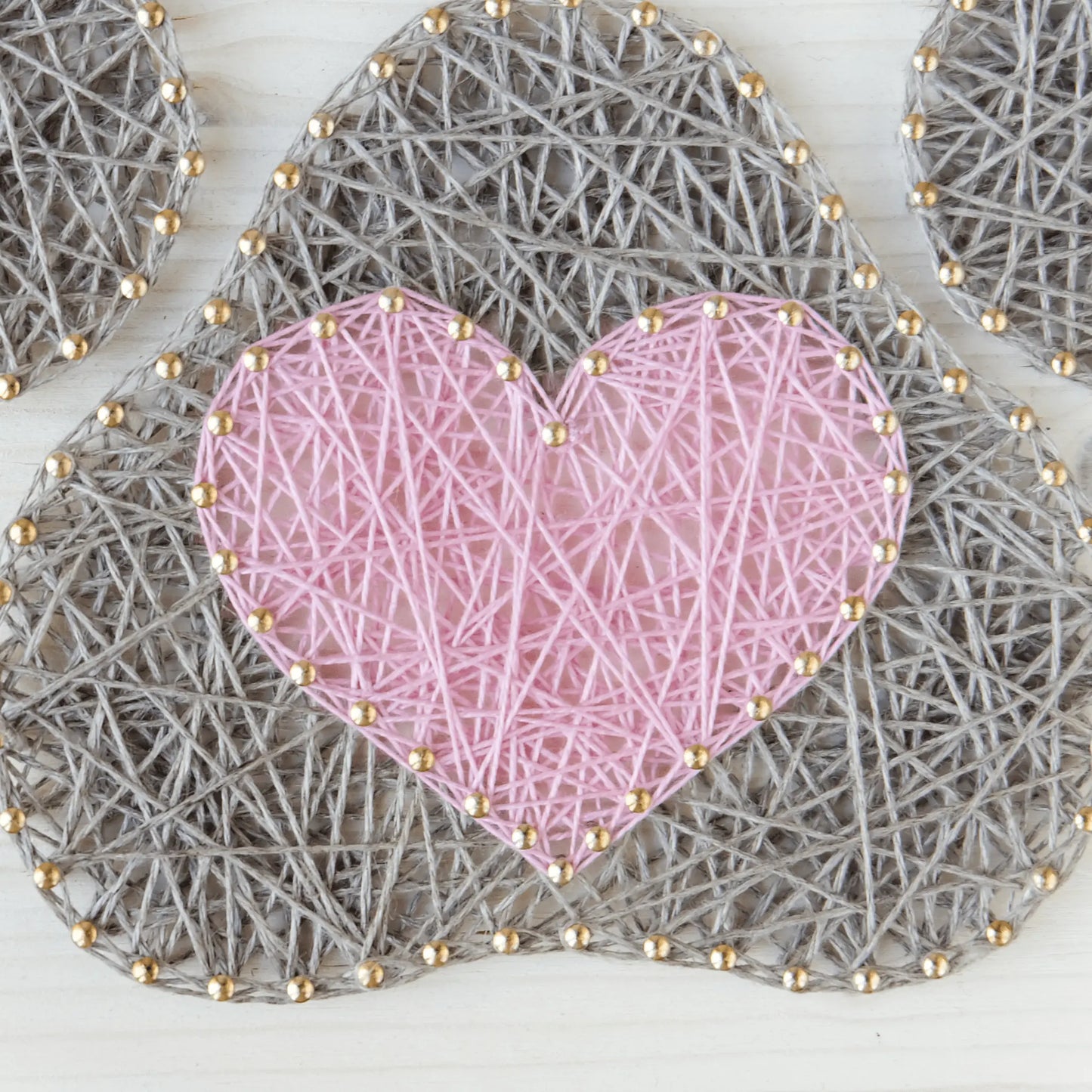 Close-up of a pink heart within a grey dog paw string art pattern, highlighting intricate nail and thread details.