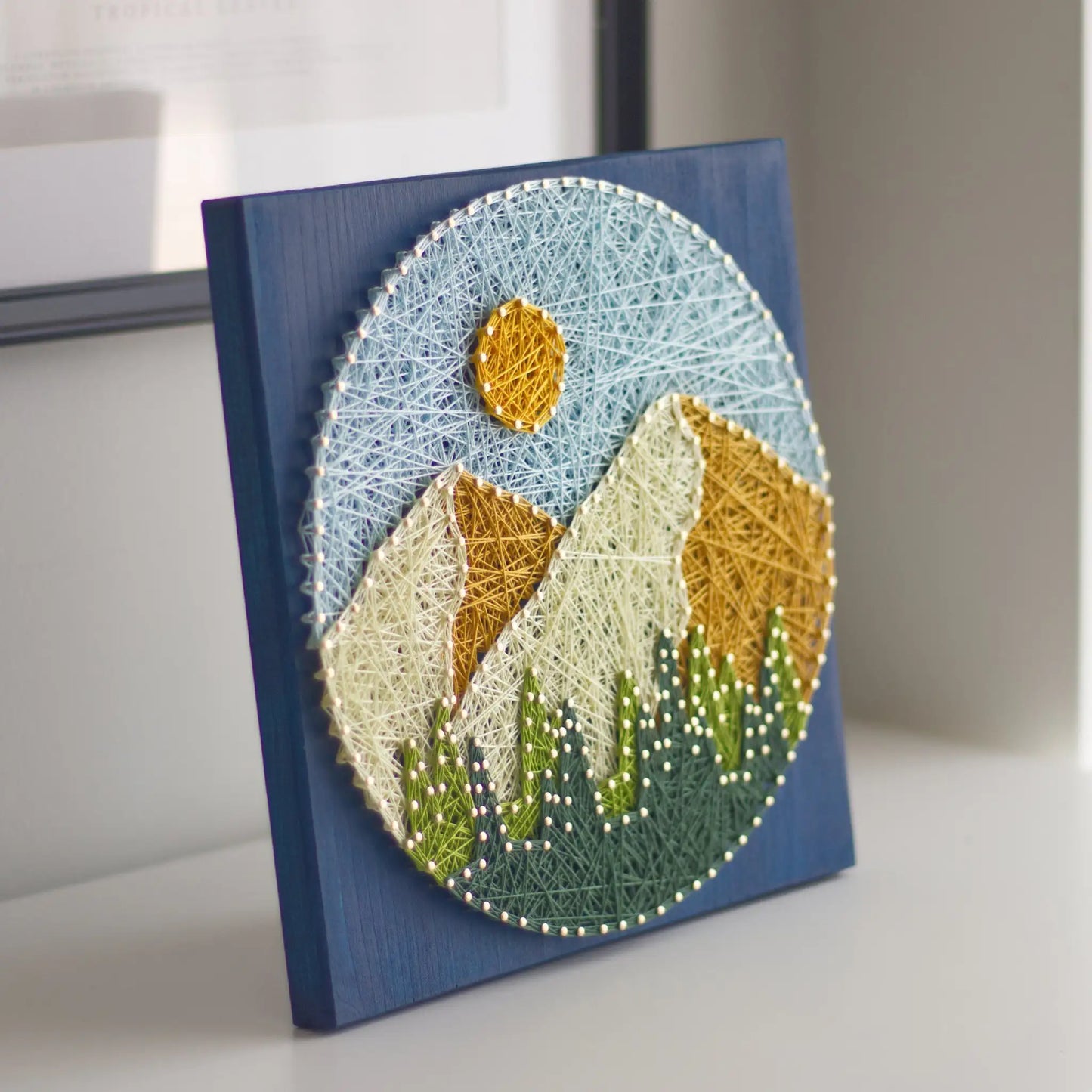 String art of mountains and sun on a blue background