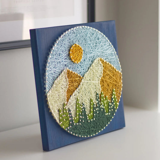 String art of mountains and sun on a blue background