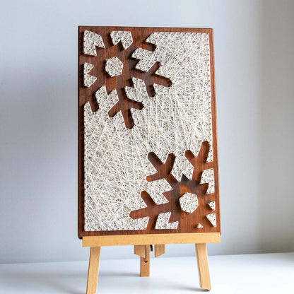 snowflake string art sign on a brown wood base