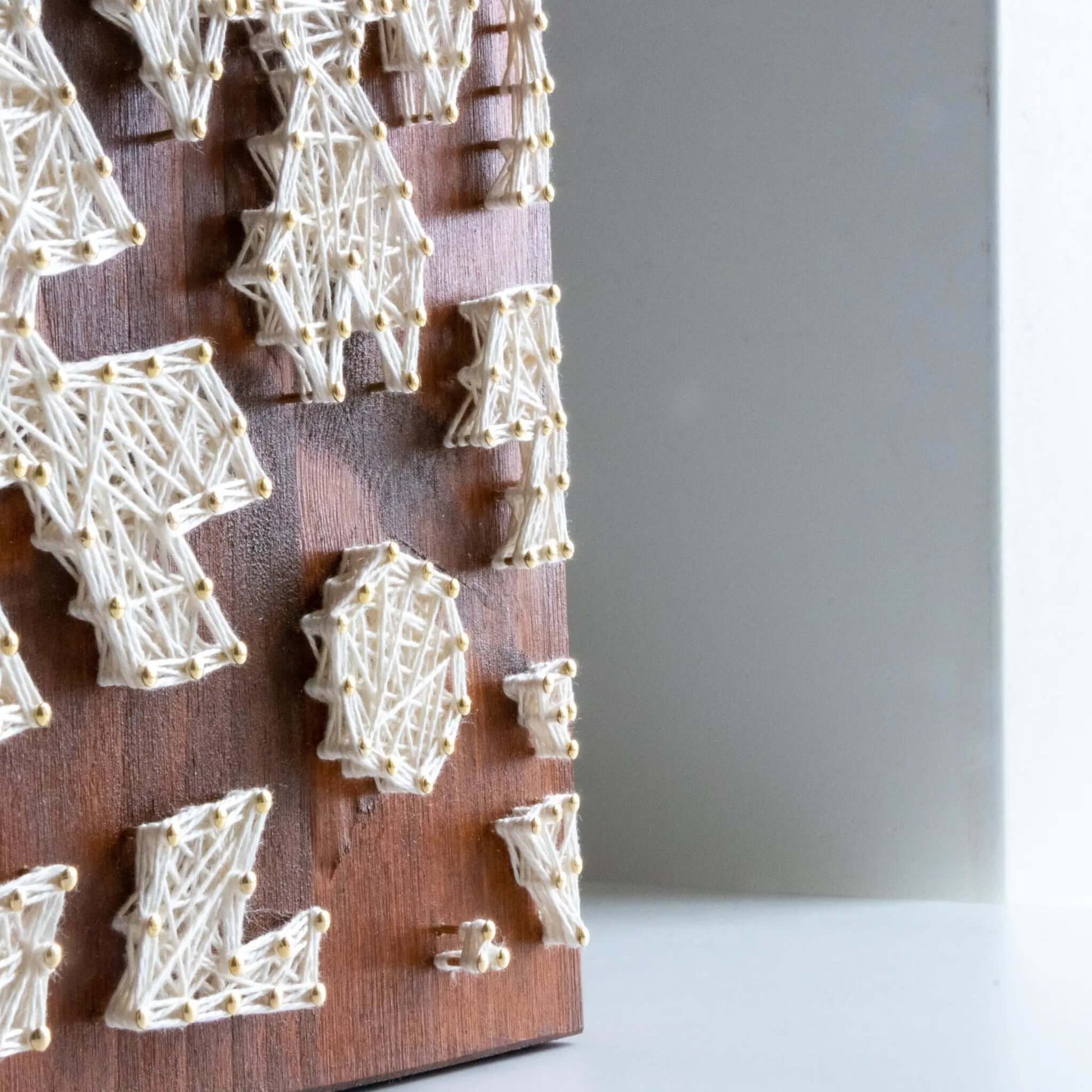 snowflake string art sign on a brown wood base