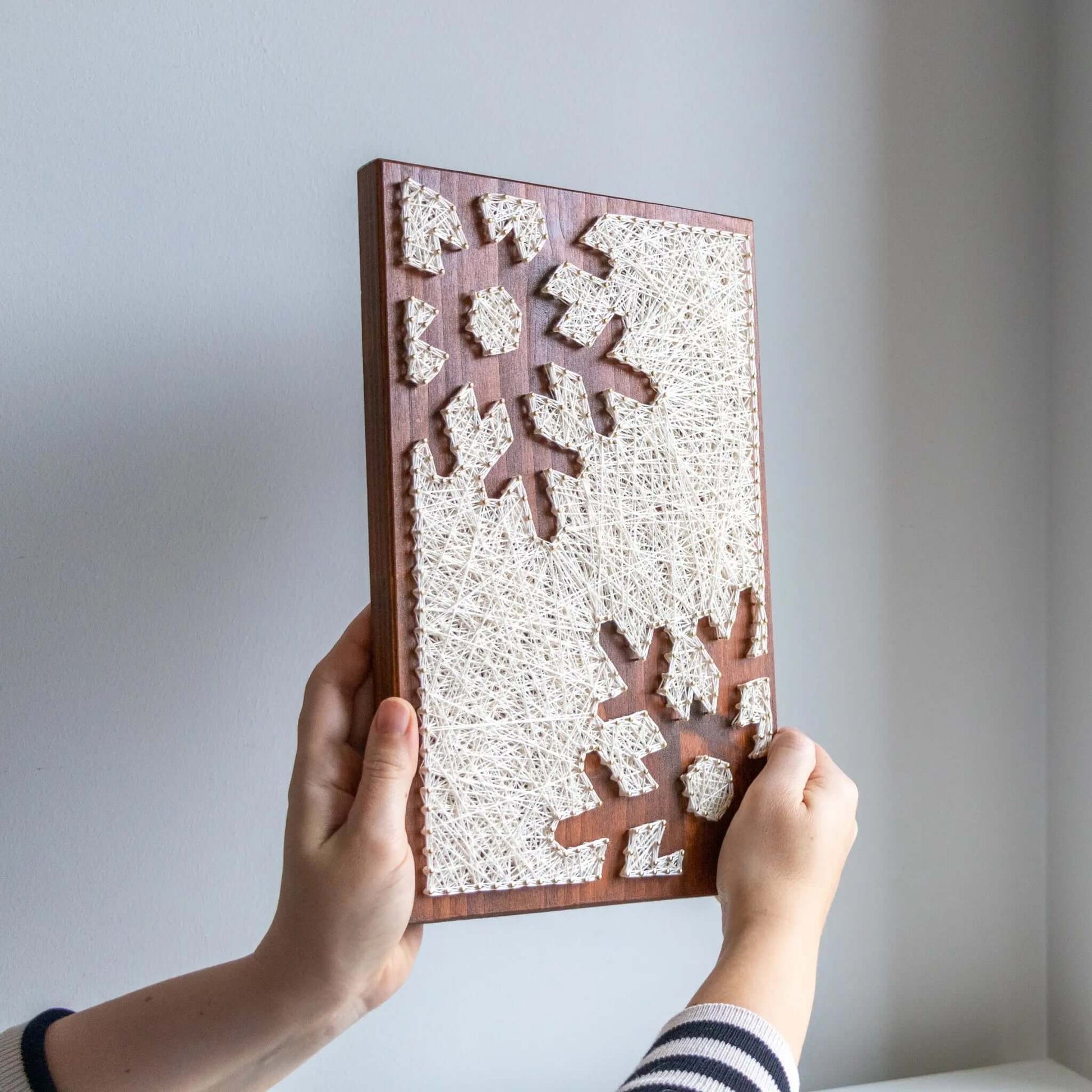 snowflake string art sign on a brown wood base