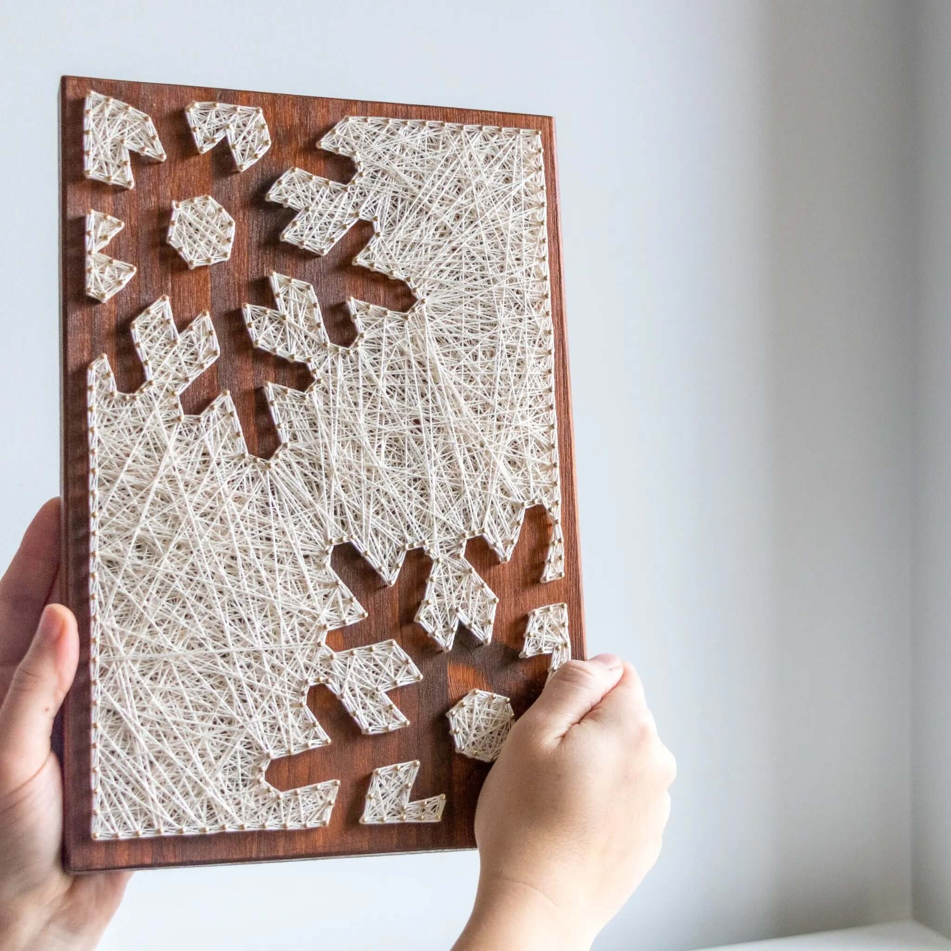 snowflake string art sign on a brown wood base