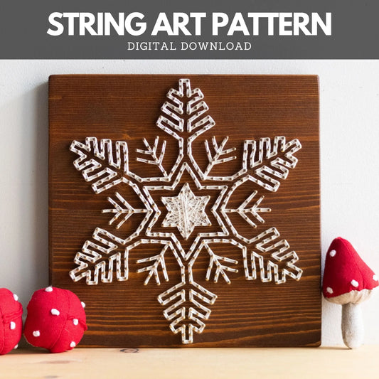 Front view of a finished snowflake string art sign made using GoodStrings' snowflake string art pattern, displayed on a dark wood board with festive mushroom decorations.