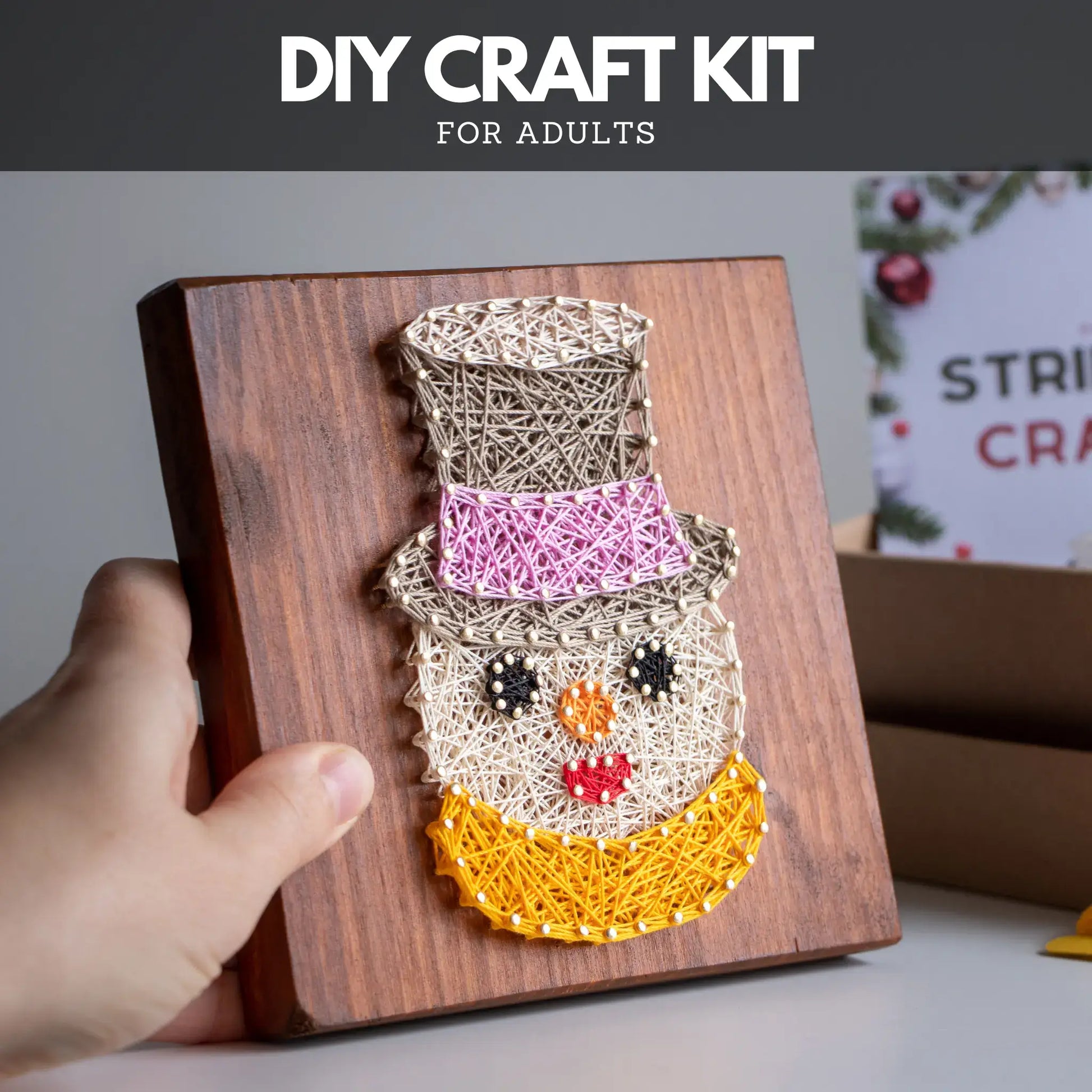 DIY craft kit for adults with a snowman string art design on a wooden board.