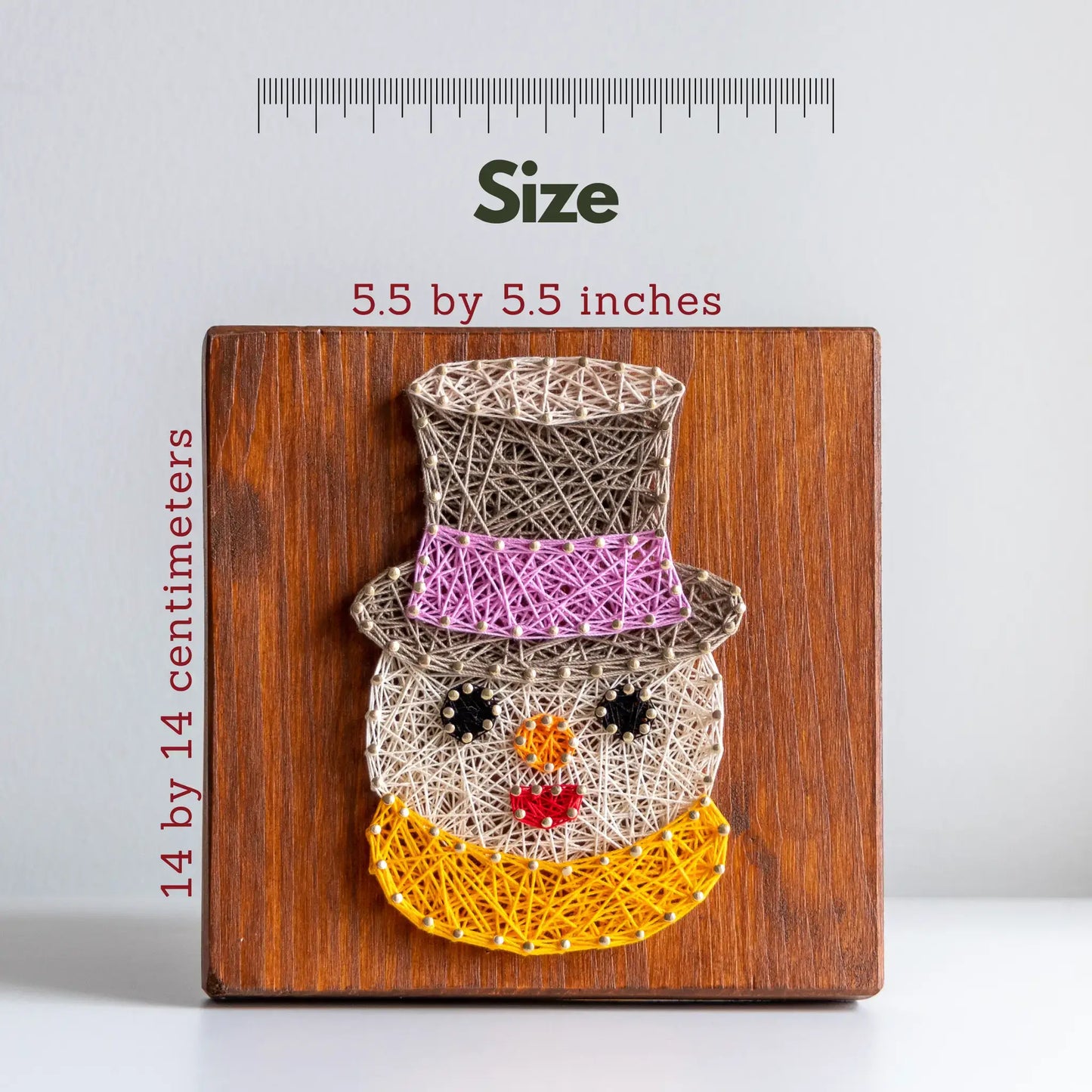 String art snowman on a wooden board with size measurement text
