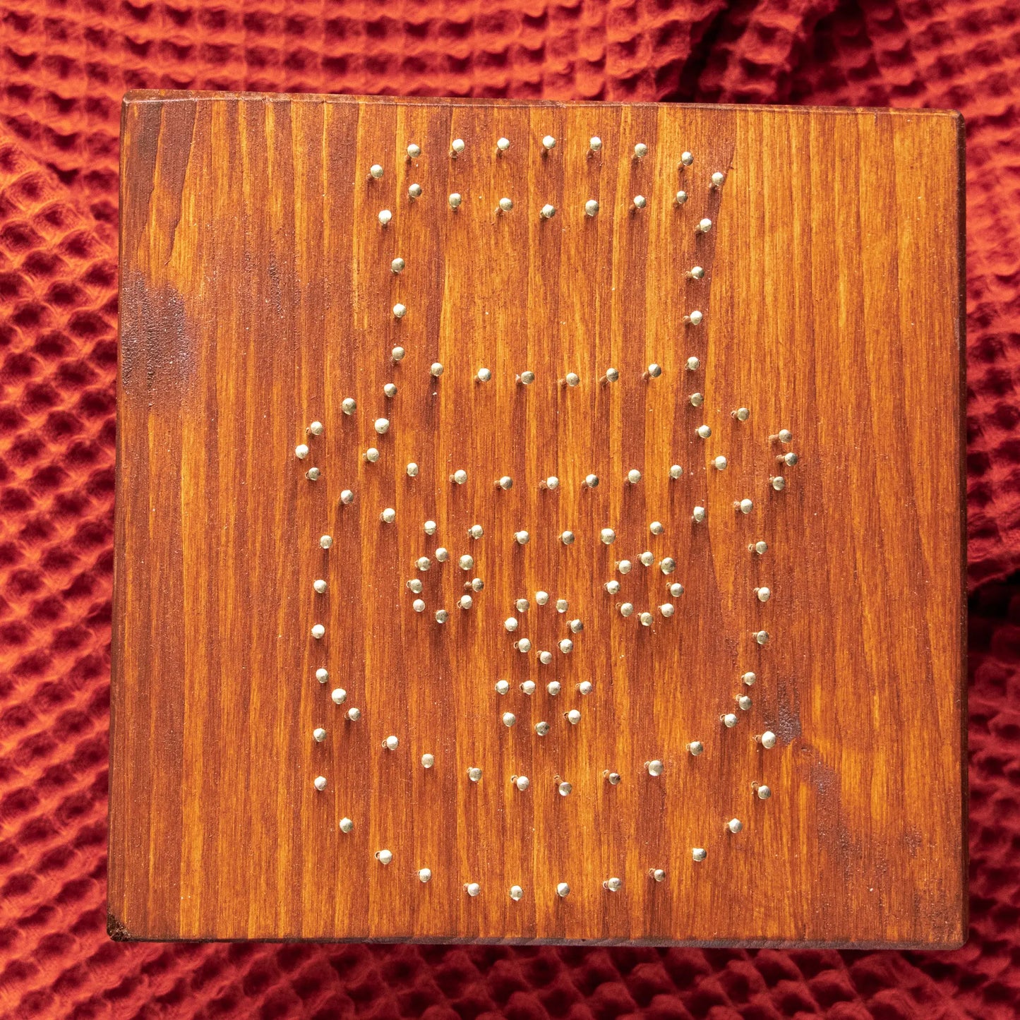 Wood base with pre-nailed outline for snowman string art pattern, showing nail placement preview.