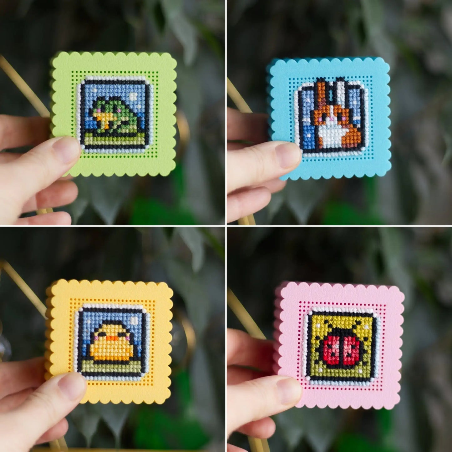 Hand holding mini cross stitch boxes showing completed embroidery designs of cat, bunny, duck, and ladybug on stitchable lids