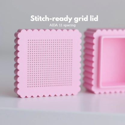 Pink mini cross stitch box lid showing perforated stitching grid with AIDA 11 spacing and removable clip inside