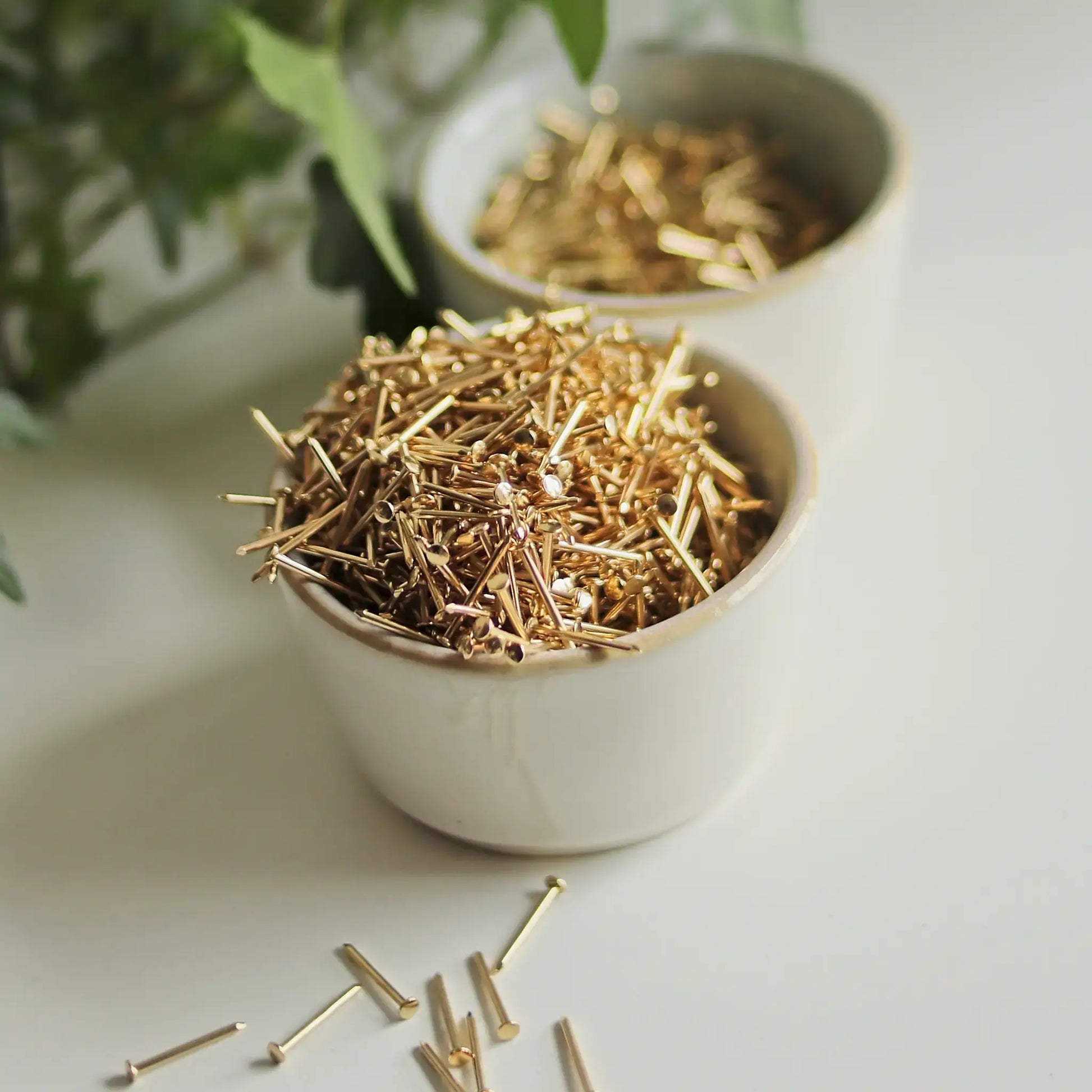 Premium brass-plated string art nails displayed in ceramic bowls — clean, durable nails for DIY string art supplies.