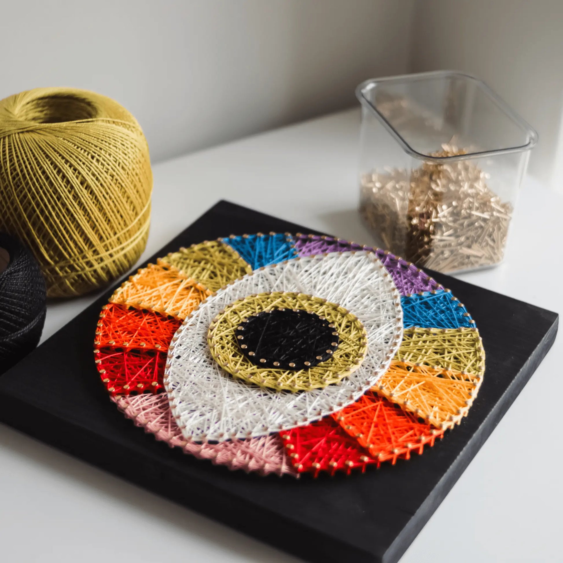 Third Eye string art - finished sign, displayed with crafting tools like colorful yarn and gold nails, emphasizing its handmade nature.