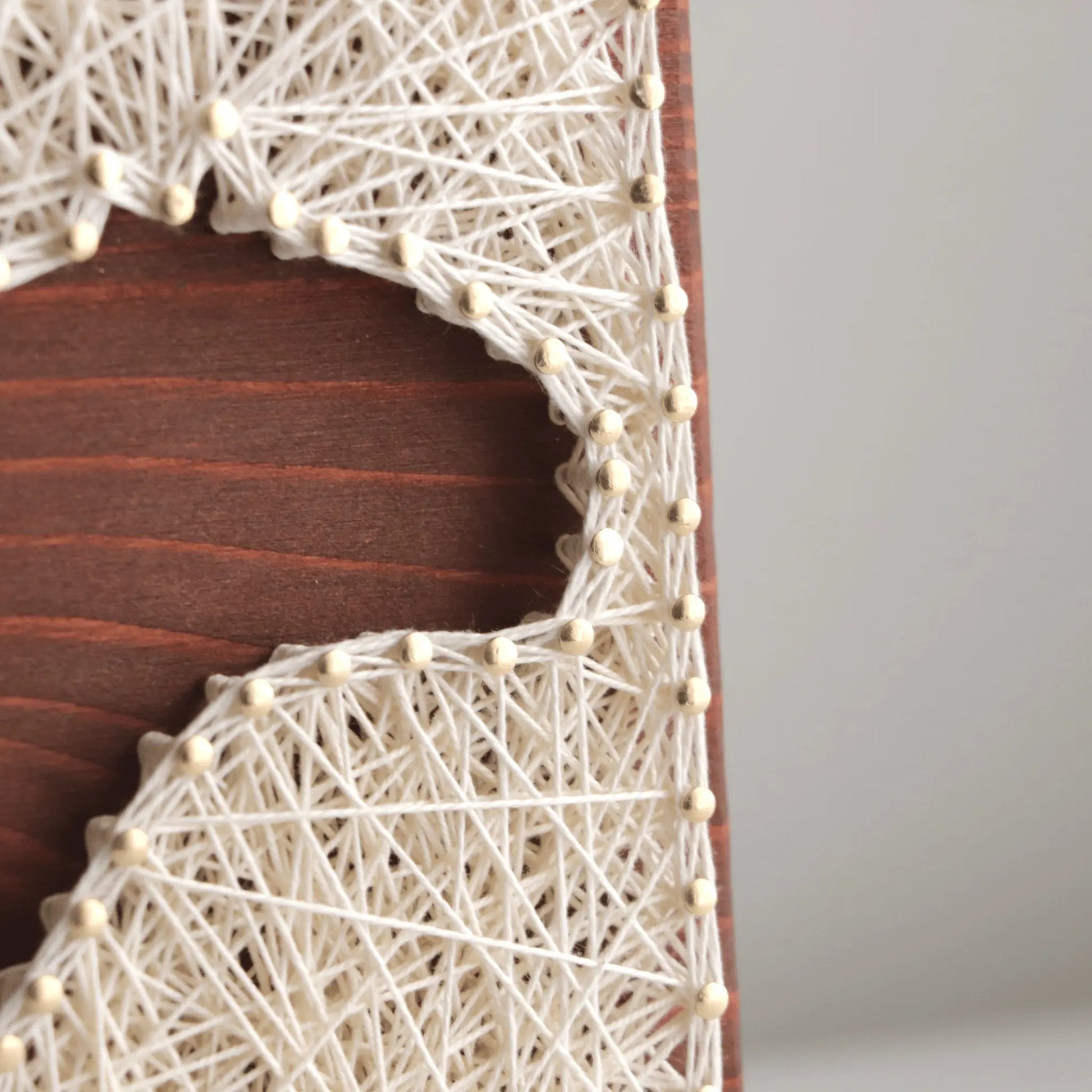 detailed string art design on a wooden board with a plain background