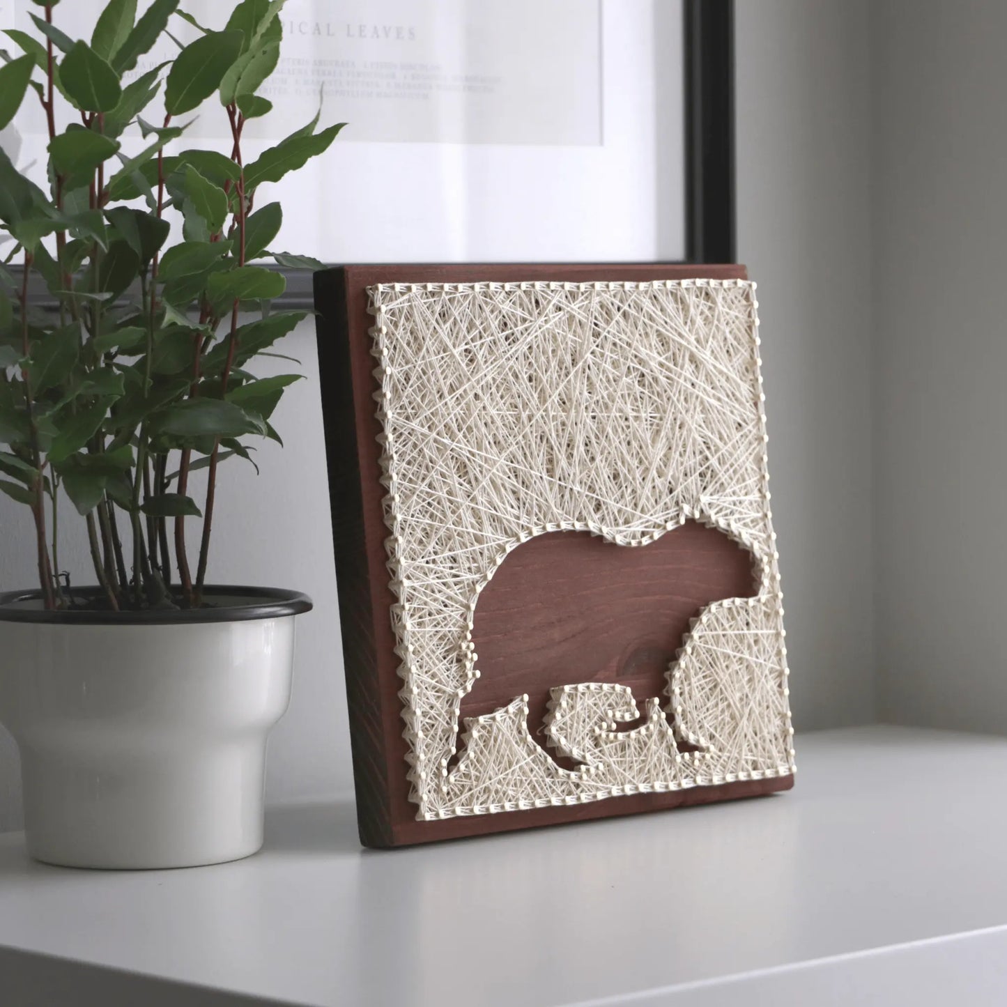 capybara silhouette string art sign on a brown background on tabletop made from ivory threads