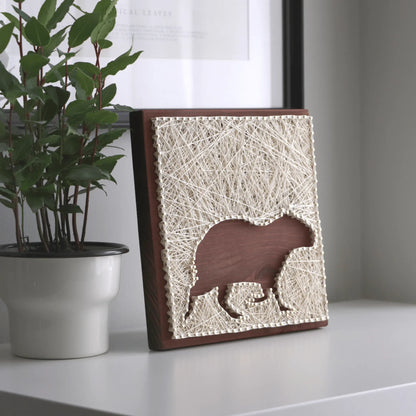 capybara silhouette string art sign on a brown background on tabletop made from ivory threads