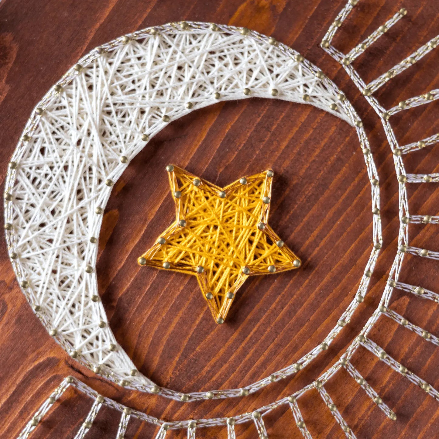 Close-up of the crescent moon and yellow star string art pattern showcasing precise nail placement and threading techniques.