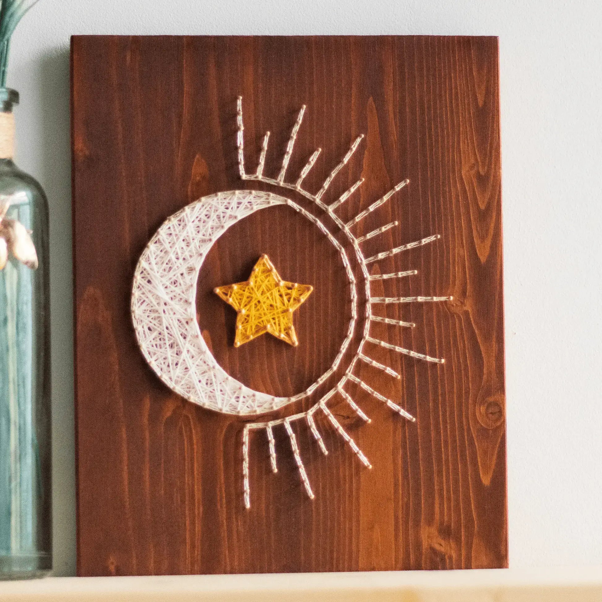 Wooden sun and moon string art decor featuring a bright yellow star in the center, ideal for adding a celestial theme to any room.