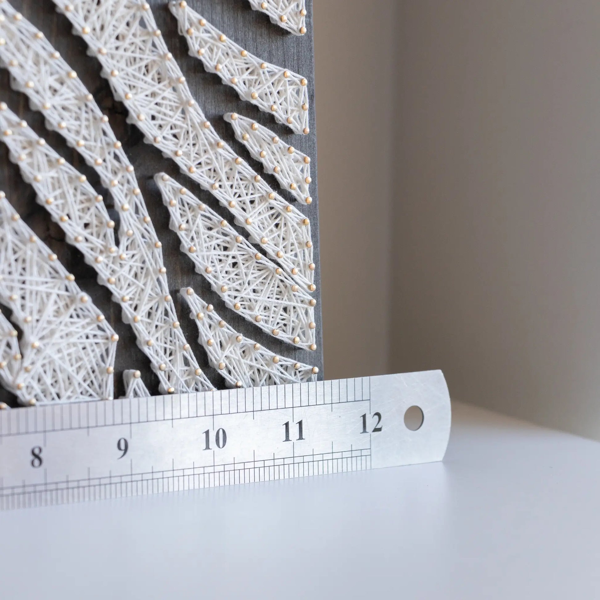 Detailed view of the lower part of the tree roots string art with a measuring ruler, showcasing the precision and craftsmanship of the design.