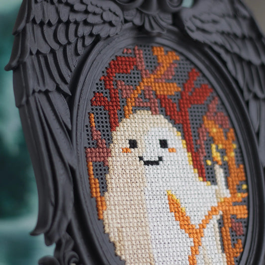 Close-up detail of black Victorian angel wing cross stitch frame showing ghost embroidery stitching detail and perforated grid surface with baroque wing texture