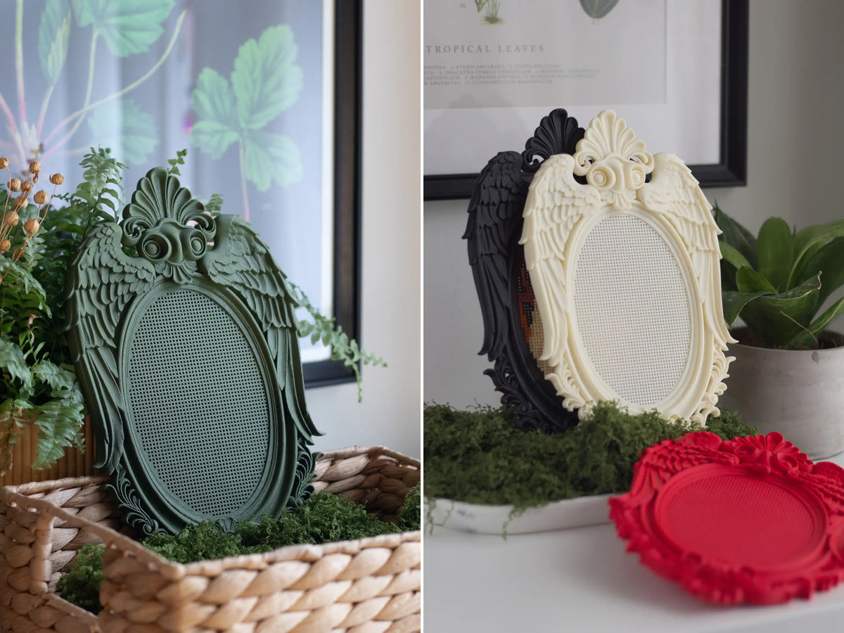 Green stitchable angel wing frame in a moss basket, and cream, black and red 3D printed frames on moss